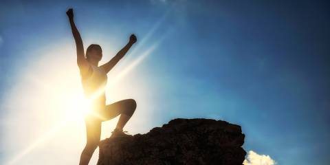 a woman climbing to the summit on a sunny day