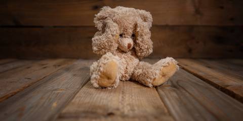 a traumatized teddy bear sitting on the floor