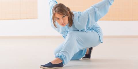 Reduce Stress with Qigong a woman practicing qi gong tai chi in a low position