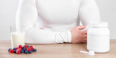 A muscular man at a table with fruits and supplements