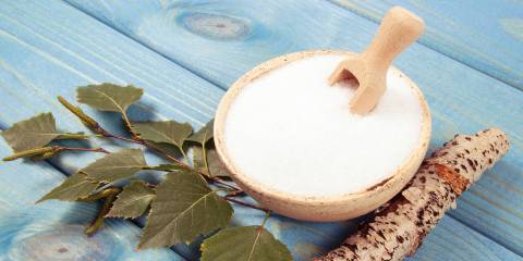 Sweet News About Xylitol Birch sugar on blue wooden background.