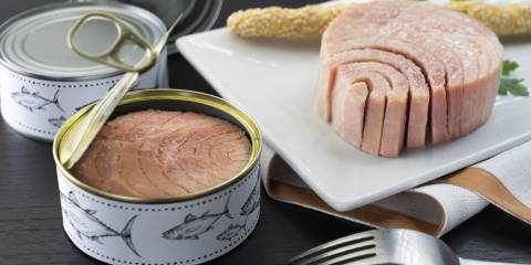 cans of tuna and some fish on a cutting board