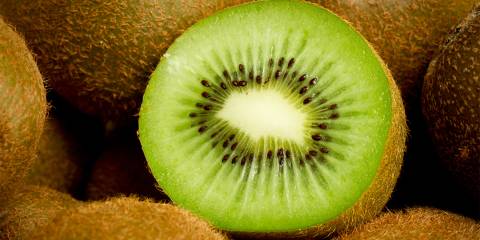 a sliced kiwi surrounded by whole kiwifruit