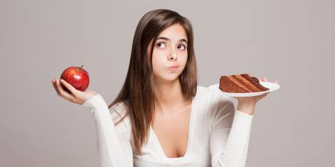 a young woman choosing between an apple and a slice of cake
