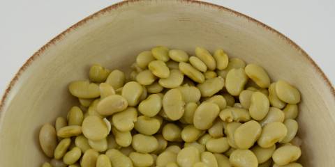 Oregano & Garlic Butter Beans Top view of lima beans in cream colored rustic bowl with a white background.