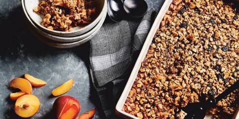 Top view of Baked Apple Maple Oatmeal in a ceramic pan, next to a stack of bowls with a serving of baked oatmeal in the top bowl.