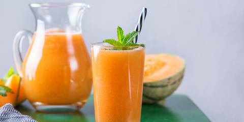 Cantaloupe Cooler a glass of melon smoothie and slices of cantaloupe