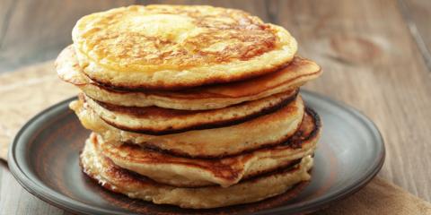 Caramelized Banana Pancakes A stack of pancakes on a grey pottery plate placed on a wooden table.