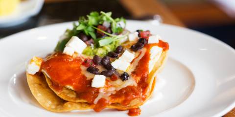 a plate of poached eggs and beans on a corn tortilla