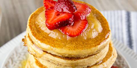 A steaming stack of pancakes with fruit on top
