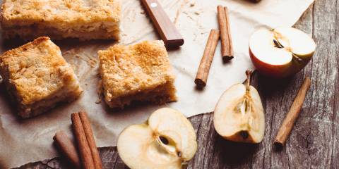 Apple Cake Apple cake with halved apples and cinnamon sticks on a rustic wooden table.