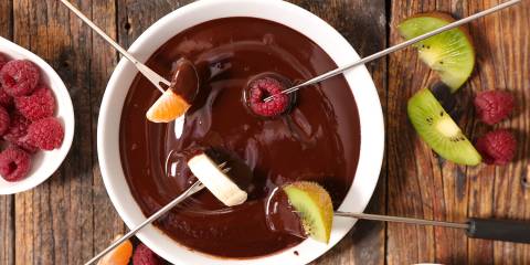 Dark Chocolate Fondue fruit getting dipped in a bowl of chocolate