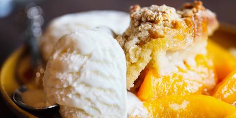 a bowl of warm peach cobbler and a scoop of vanilla ice cream