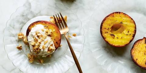 Grilled Peaches with Ginger Cream and Walnut Praline on a glass plate with brass fork.