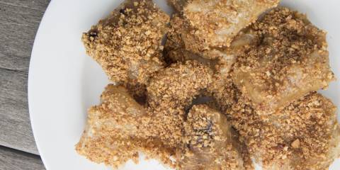 A plate of puffed mochi drizzled in syrup and covered in nuts