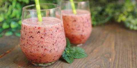 two berry smoothies in glass cups with straws