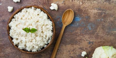Cauliflower Rice with Zucchini, Parmesan Cheese, and Basil A wooden bowl filled with cauliflower rice.