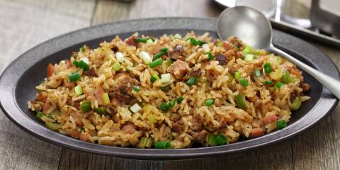 a bowl of rice with sausage, spices, and chopped vegetables