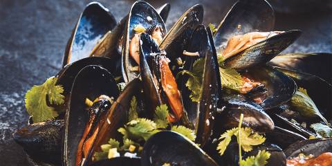 Grilled mussels served on a dark platter