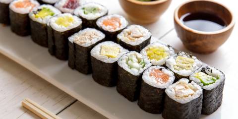 Mini maki sushi platter on white wooden table.