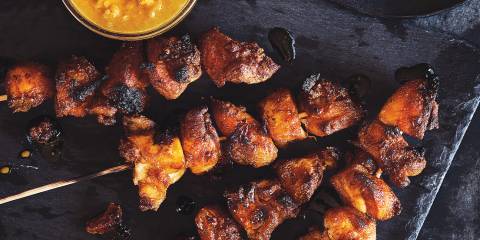 Malaysian Chicken Satay Chicken Satay skewers with a bowl of peanut dipping sauce on the side