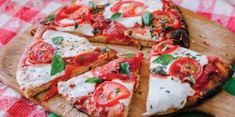 Margherita Flatbread Pizzas Margherita Flatbread Pizza on a wooden pizza board, cut and ready to serve.
