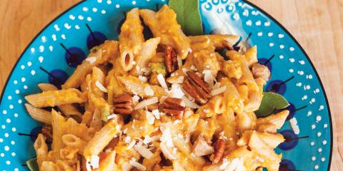 A bowl of penne with butternut squash and chicken sausage, garnished with sage