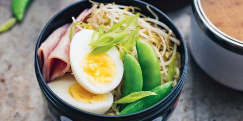 Ramen Bento a bowl of noodles topped with ham, egg, and snow peas