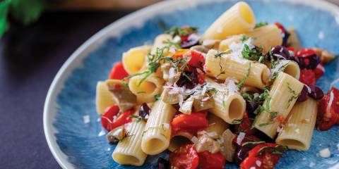 Rigatoni with Fresh Cherry Tomatoes and Olives on a blue plate ready to serve.