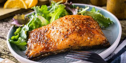pan-seared salmon served with lemons over a mix of greens