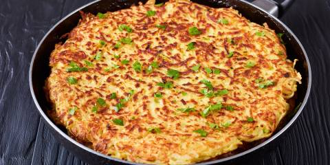 potato pancakes cooking in the pan with greens