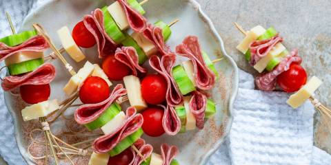 a plate of skewers with cheese and cherry tomato