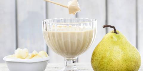 Chunks of pear being dipped into a goblet of Cinnamon Cheesecake Fondue. 