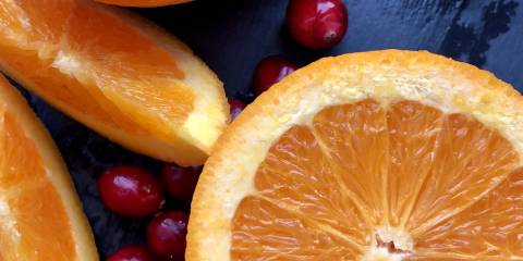 Cranberry Orange Pops Cranberries and sliced oranges on a dark blue background.
