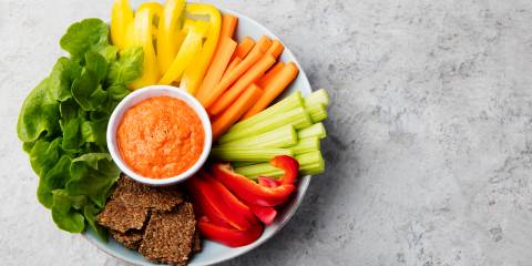 Assorted fresh vegetables with Roasted Red Pepper & Almond Dip. Stone background
