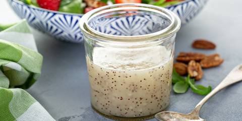 Poppy Seed Dressing a jar of poppy seed dressing in front of a strawberry salad