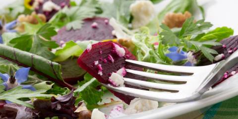 a plate of beet salad with baby greens and goat cheese