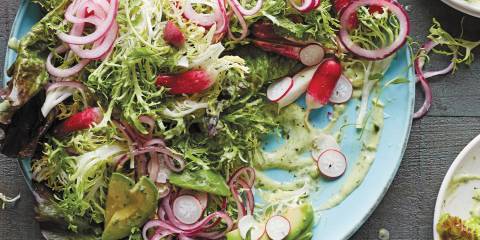 Frisee salad on a blue plate with a gray wood background.