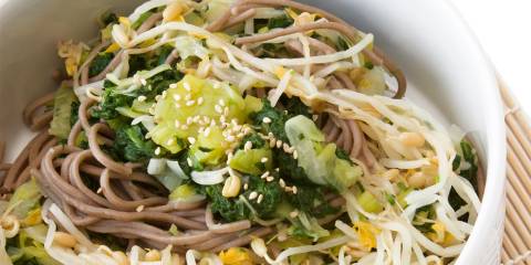 a bowl of soba noodles and leafy greens