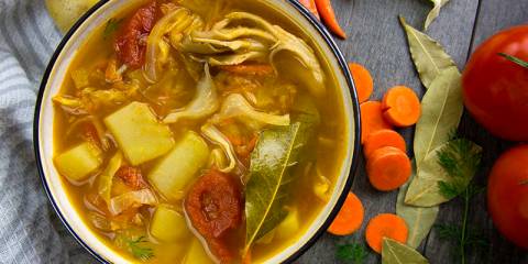 a hot bowl of soup with cabbage, potatoes, and other vegetables