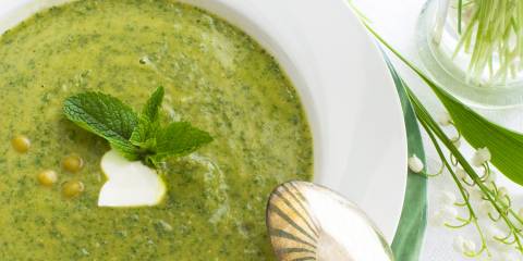 a bowl of pureed pea soup with mint