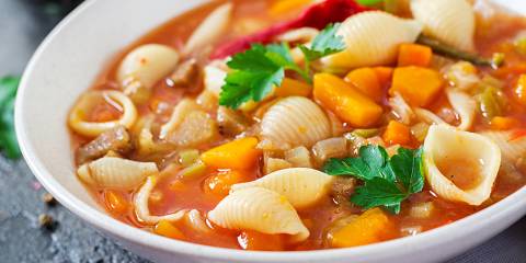 a bowl of red minestrone with pasta