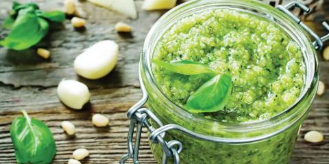 A canning jar of fresh basil pesto with garlic and cheese