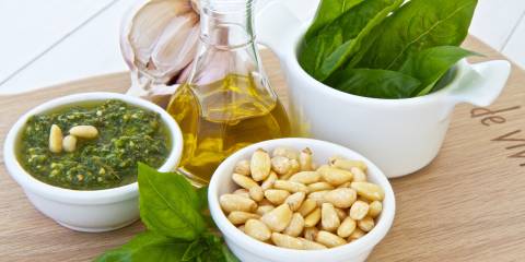 Bowl of pesto with the ingredients displayed on a wood cutting board. 