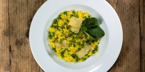 a bowl of risotto with leeks, peas, garnish, and cheese