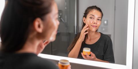 Manuka Honey A woman adding honey to her skin in front of a bathroom mirror.