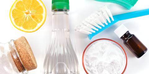 5 Essential Oils For Cleaning Your Home a sponge, a brush, vinegar, a lemon, baking soda, and a bottle of essential oil