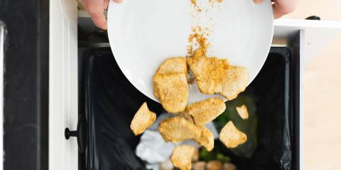 someone dumping good food into the kitchen trash