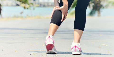 Woman holding calf during a muscle spasm while running.