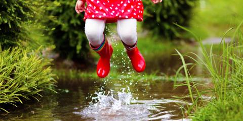 Natural Movement Young girl with red rubber boots jumping up from a creek.